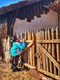 Rear view of woman standing against wood