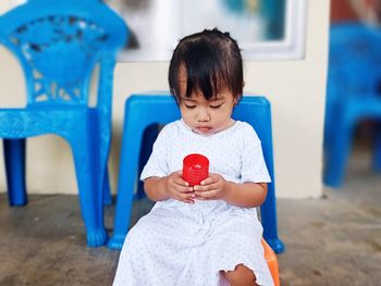 Full length of cute girl sitting against blue wall