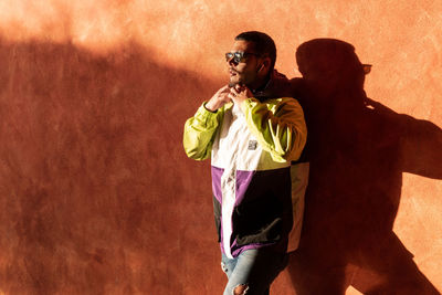 Man wearing sunglasses standing by wall