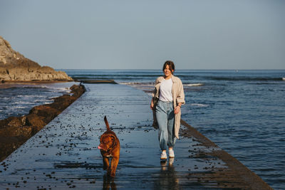 Man with dog in sea against sky