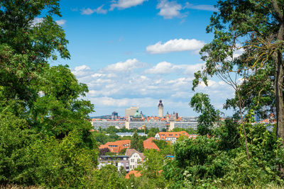 Trees and townscape against blue sky