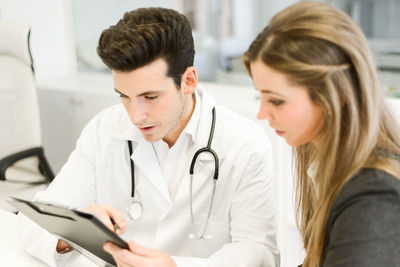 Doctor examining medical reports with patient at hospital