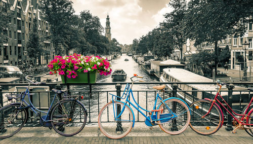 Bicycle parked by railing in canal amidst buildings in city