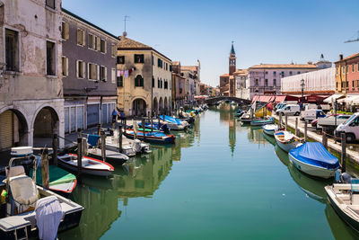 Boats moored in canal amidst buildings against sky