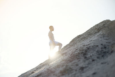 Low angle view of man standing on rock against sky