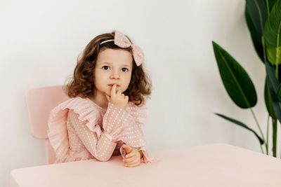 Portrait of a little girl in festive clothes sitting thoughtfully at a table