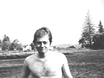 Portrait of shirtless man against trees against clear sky