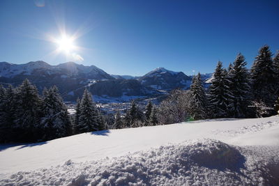 Scenic view of snow covered mountains against bright sun