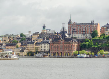 Buildings by river against sky in city