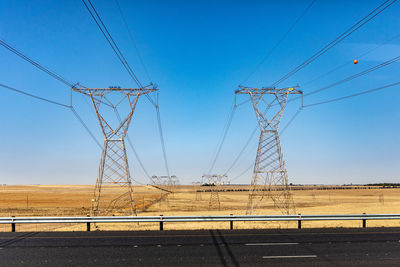 Electricity pylon on field against clear sky