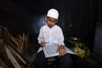 Close-up of boy reading koran in darkroom