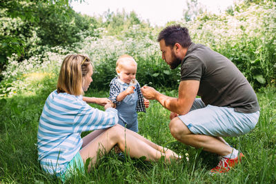 Side view of young woman with daughter on grass