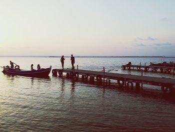 People on beach against sky during sunset