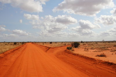 Dirt road on desert against sky