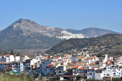 Townscape by mountains against clear blue sky