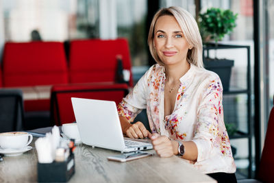 A beautiful girl works online on a laptop, sits in a cafe or office