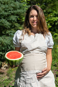 Happy woman holding strawberry while standing outdoors