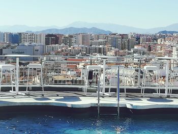 Sailboats moored in harbor by buildings against clear sky