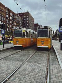 View of railroad tracks by city street against sky