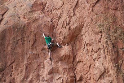 Rear view of man climbing rocky mountain