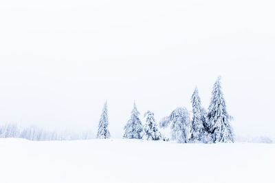 Snow covered land against clear sky during winter