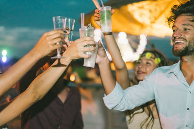 Friends toasting drink in party at night