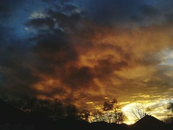 Low angle view of silhouette trees against dramatic sky