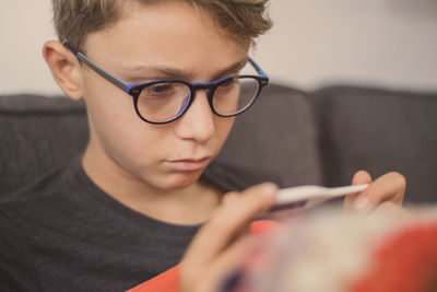 Close-up of boy checking thermometer at home