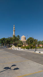 Street amidst buildings against clear blue sky