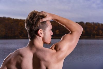 Portrait of shirtless man standing against sky