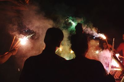 People playing with fireworks outdoors at night