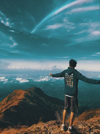 Rear view of man standing on mountain against sky