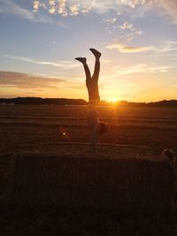 Silhouette of woman standing on field at sunset