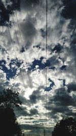 Low angle view of power lines against cloudy sky