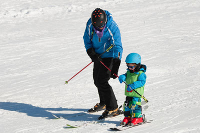 Mid adult man and his son skiing on snow covered field