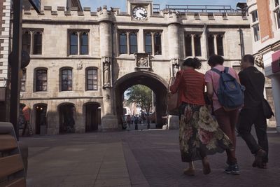 Rear view full length of people walking towards guildhall and stonebow in city