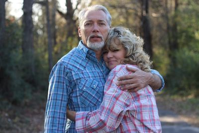 Portrait of senior couple embracing against tree