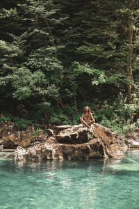 Shirtless man doing yoga on rock in front of tara river