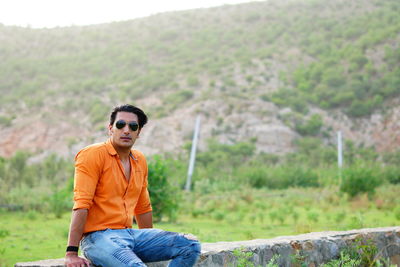 Portrait of handsome mid adult man sitting on stone wall