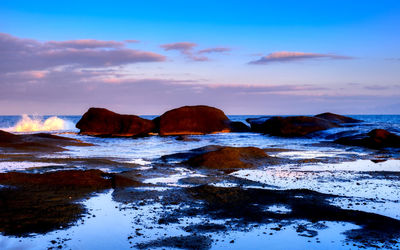 Rock formations in sea against sky during sunset