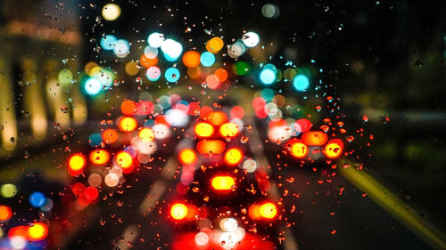 Illuminated street seen through wet glass window