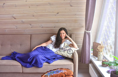 Young woman sitting on sofa at home