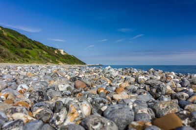 Surface level of stones at beach against blue sky