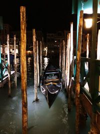 Wooden post in canal amidst buildings at night