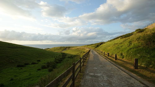 Road amidst field against sky