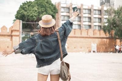 Young woman photographing with mobile phone standing in city