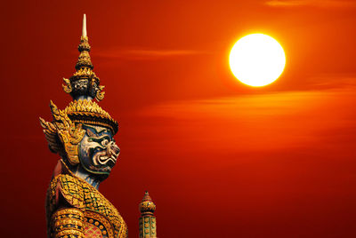 Low angle view of statue against orange sky