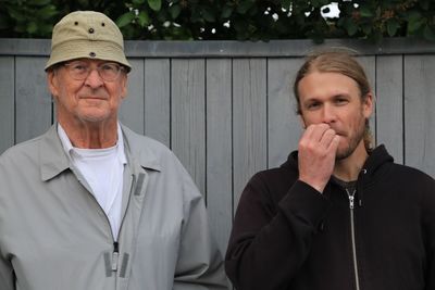 Portrait of father and son standing against wooden fence at yard