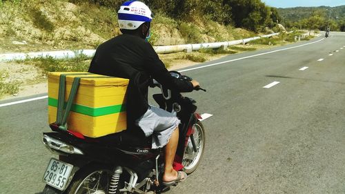 Rear view of man riding motorcycle on road