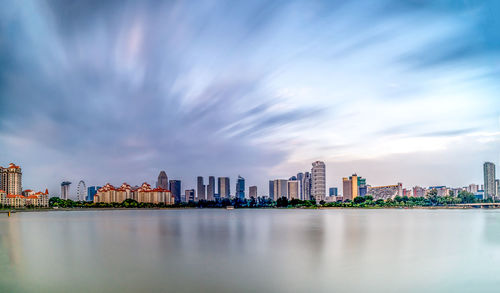 City at waterfront against cloudy sky